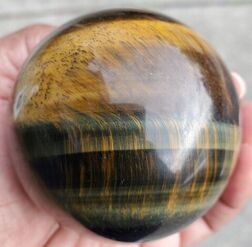 A yellow tiger's eye sphere held in hand